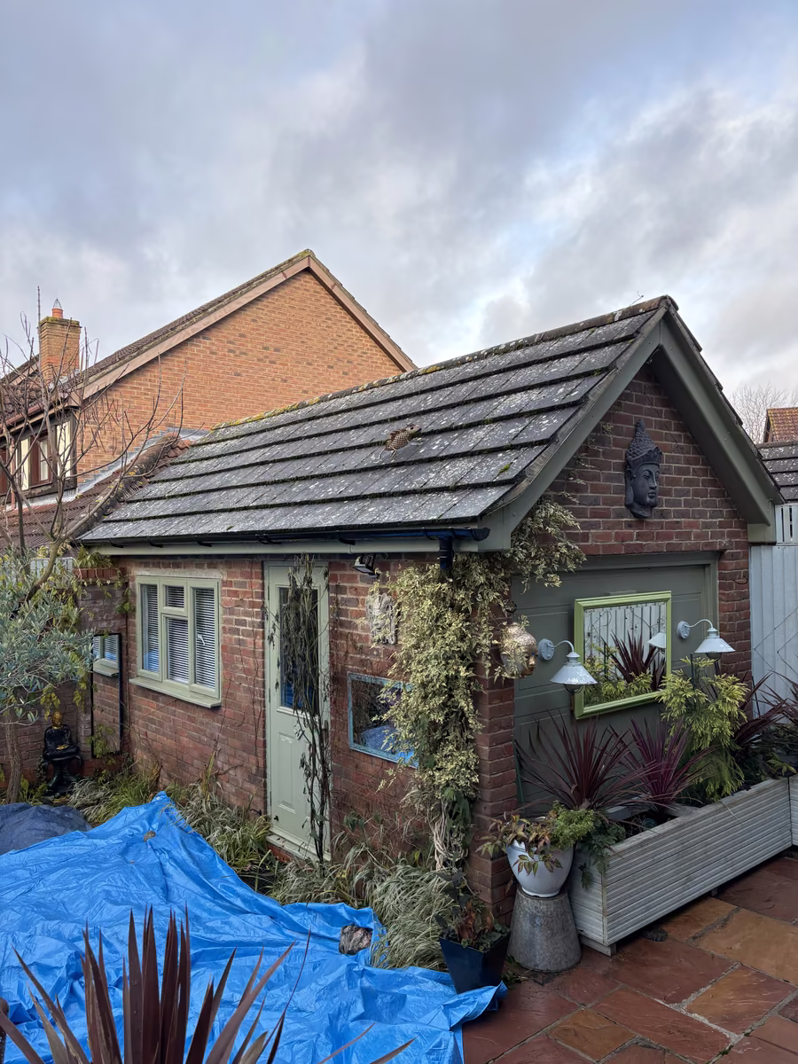 Tiled outbuilding roof with moss and algae before cleaning